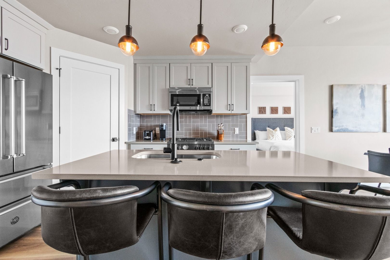 A modern kitchen with a central island, stainless steel appliances, and pendant lighting.
