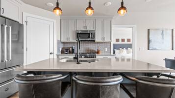 A modern kitchen with a central island, stainless steel appliances, and pendant lighting.