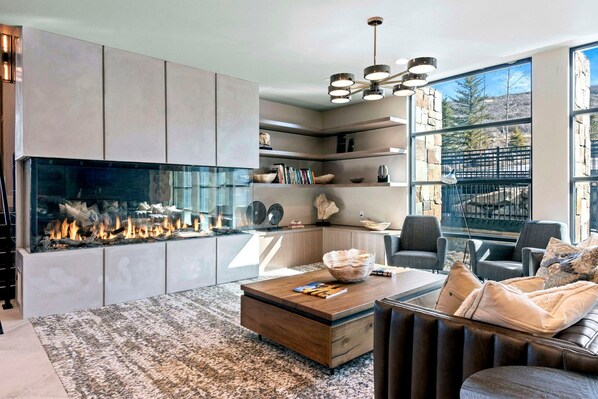 Uma sala de estar moderna com lareira, mesa de centro, sofá e estante de livros.