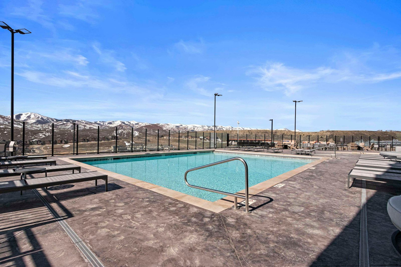 A pool area with a view of snow-capped mountains, surrounded by lounge chairs and tables.
