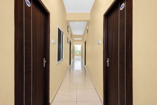 Un couloir avec des portes numérotées 305 et 301, qui mène à un espace intérieur lumineux.
