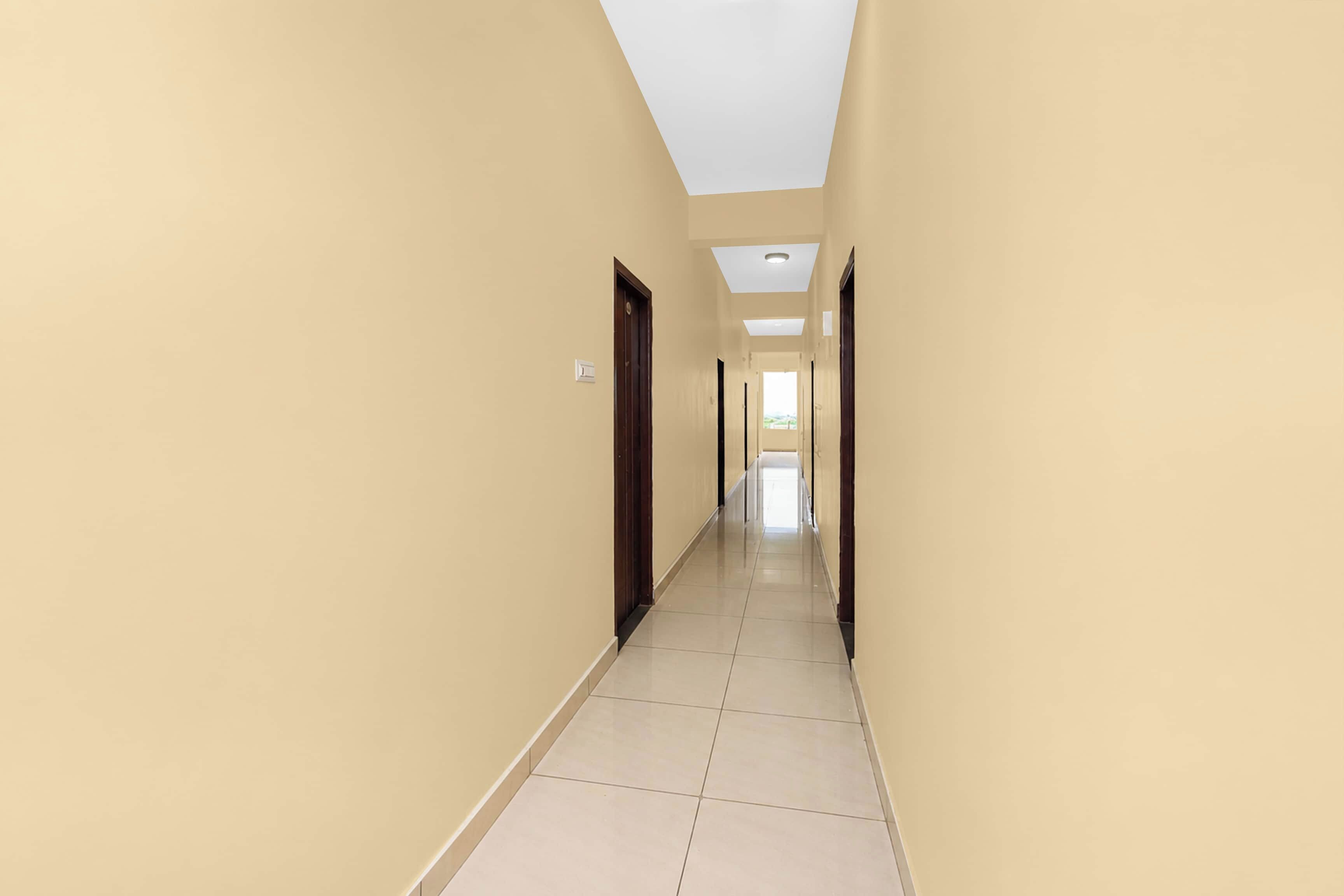 A long, narrow hallway with a tiled floor and beige walls.