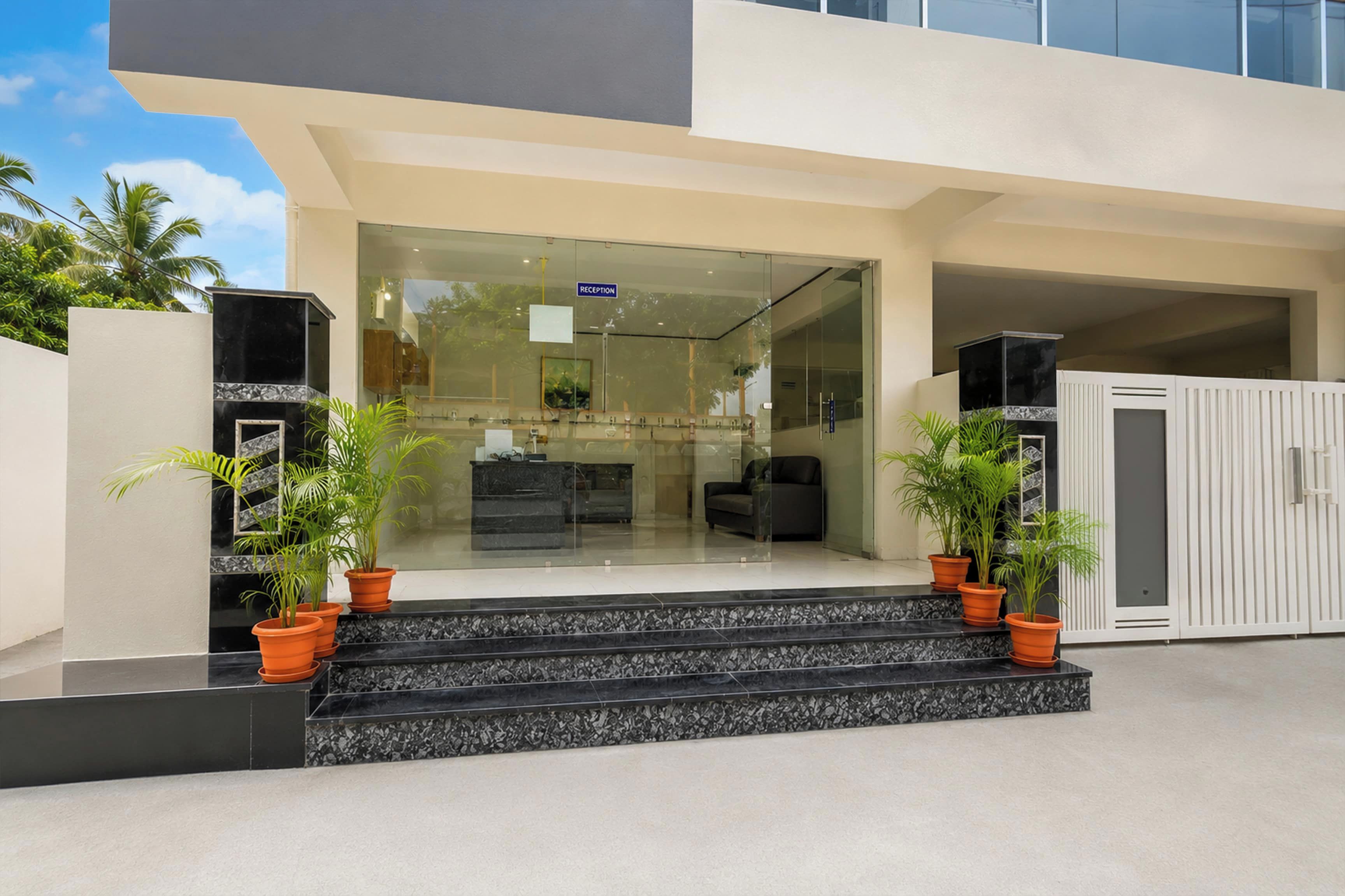 A modern building entrance with a reception desk, glass doors, and potted plants.