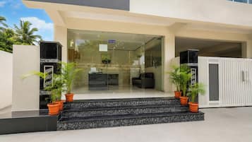 A modern building entrance with a reception desk, glass doors, and potted plants.