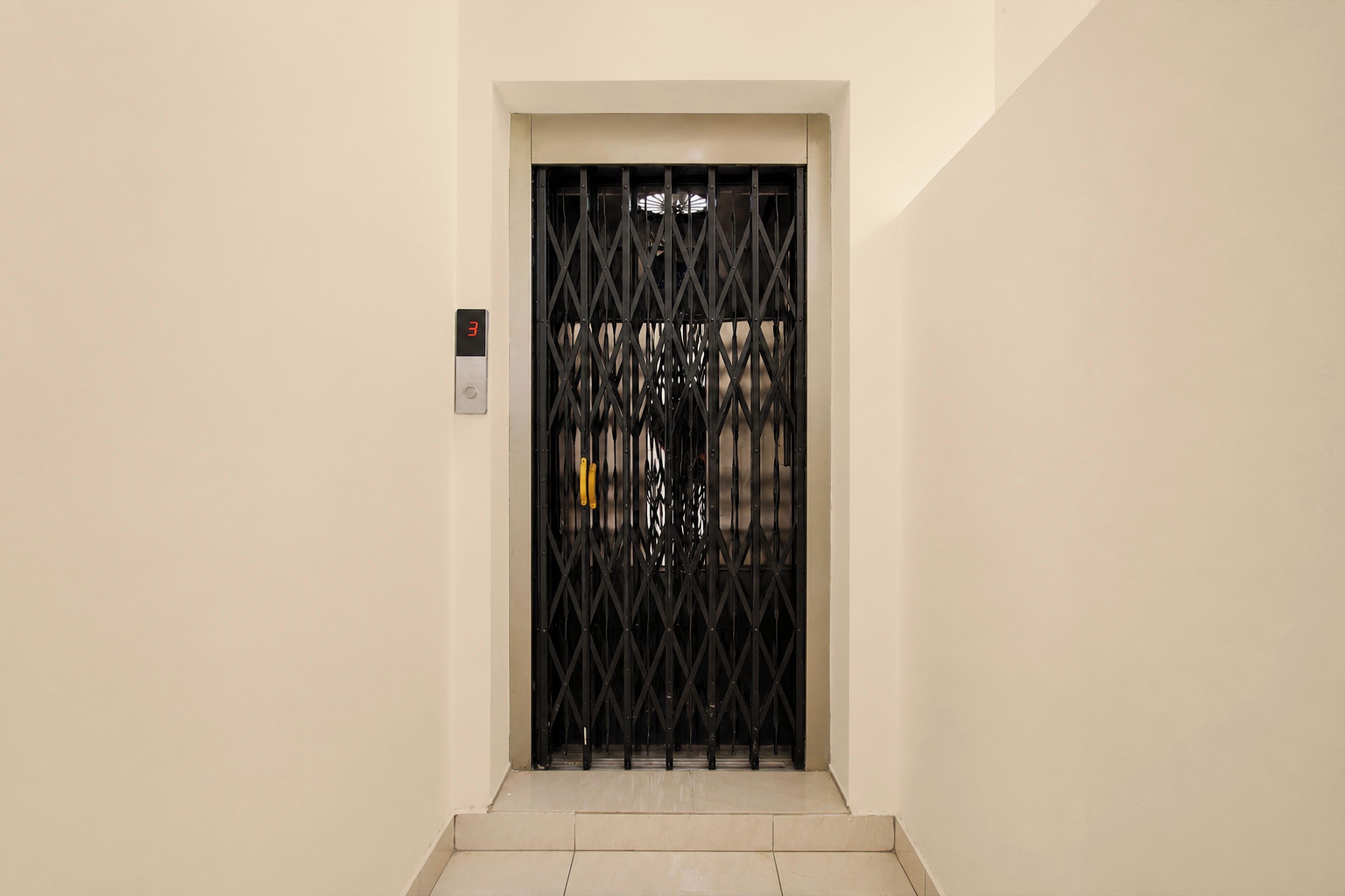 A hallway with a black metal gate and a digital elevator control panel.