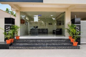A hotel reception area with a reception desk, seating, and potted plants. - Super Hotel O Temple Road Vemulavada (Karimnagar)