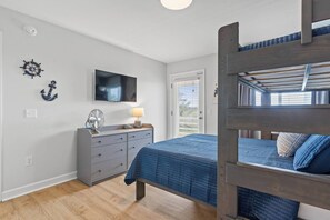 A bedroom with a bunk bed, a desk with a lamp, a TV, and nautical-themed wall decor. - Waterfront 5br/4.5ba Canal Home Close to The Beach (Ocean Isle Beach)