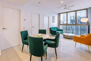 Un interior moderno con una mesa redonda, sillas verdes, una silla amarilla y un ventilador de techo.
