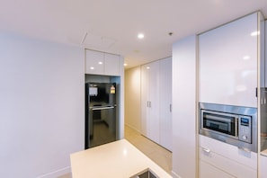 Una cocina moderna con refrigerador integrado, horno y muebles blancos.