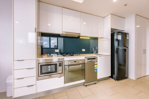 A modern kitchen with white cabinetry, stainless steel appliances, and a black refrigerator. - 1 Bedroom Cityside Residence (Fortitude Valley)