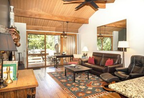 A spacious living area with a wooden ceiling, a fireplace, a dining table, and a leather sofa. - Sedona Oak Creek Villa -w/ AC & Heat (Sedona)