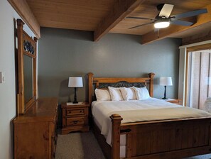 A bedroom with a wooden bed, two bedside tables with lamps, a ceiling fan, and a large mirror. - Sedona Oak Creek Villa -w/ AC & Heat (Sedona)