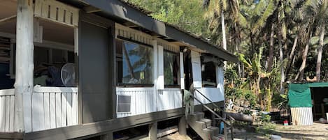 A wooden structure with a porch, a fan, and a staircase leading to an upper level.