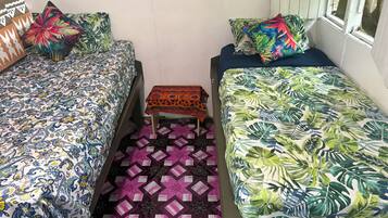 A room with two beds, each with a patterned bedspread, a small table, and a window with a view.