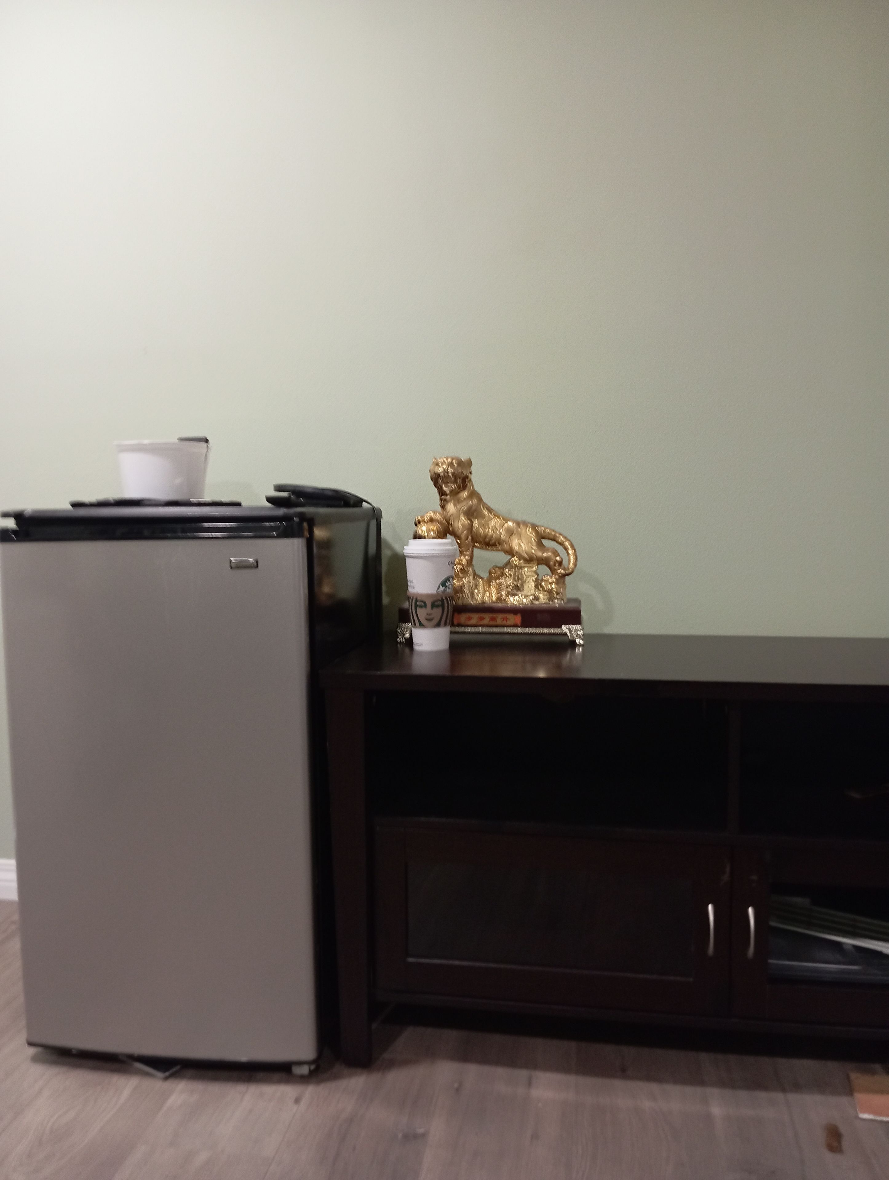 A kitchenette with a refrigerator, a coffee maker, and a decorative golden lion statue.