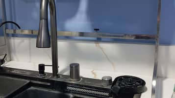 A kitchen sink with a faucet, a sponge, and a bottle of dish soap.