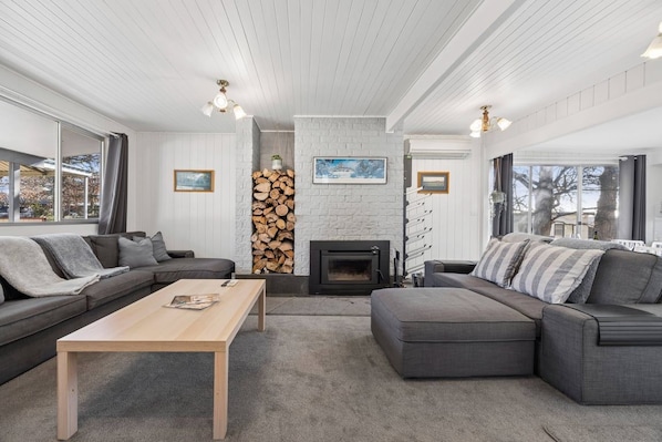A modern living room with a fireplace, grey sofas, a wooden coffee table, and a white brick accent wall.