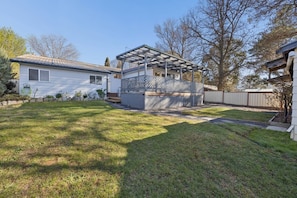 A residential property with a covered patio, a fenced yard, and a house with a sloped roof.