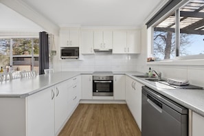 A modern kitchen with white cabinetry, a stainless steel oven, and a dishwasher.