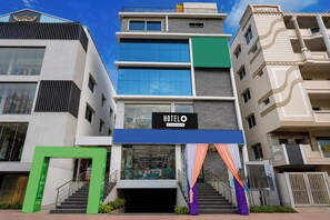Un hotel de varios pisos con un llamativo letrero que dice 'HOTEL', una escalera que conduce a la entrada y un diseño arquitectónico moderno.