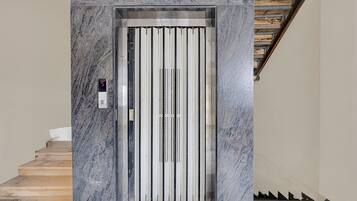 An elevator with a digital display, metallic interior, and a marble wall.