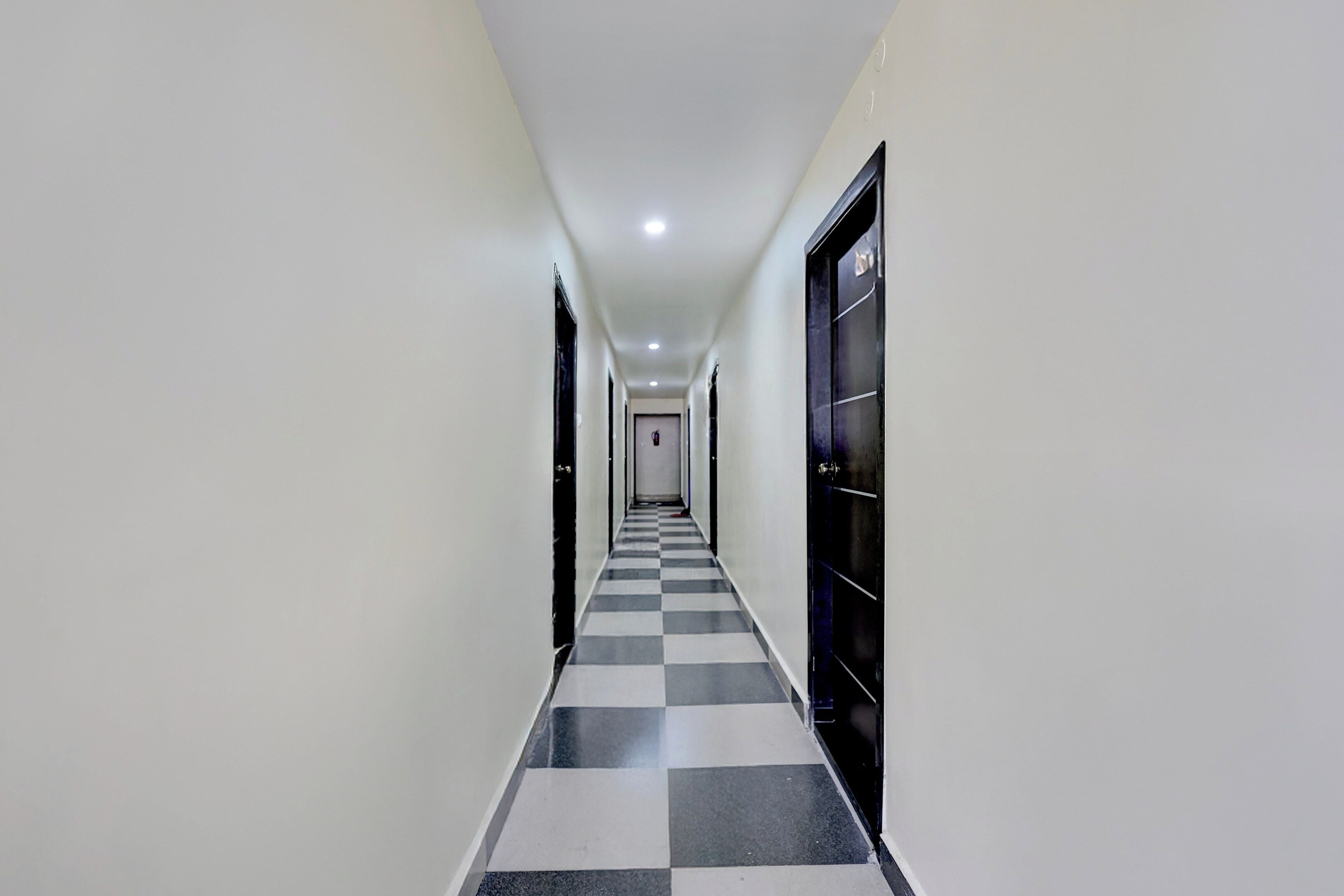 A hallway with a checkered floor, white walls, and doors on both sides.