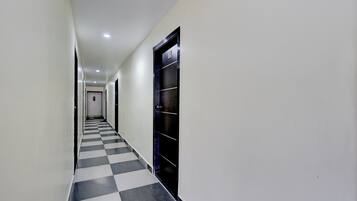 A corridor with a checkered floor, white walls, and doors on both sides.