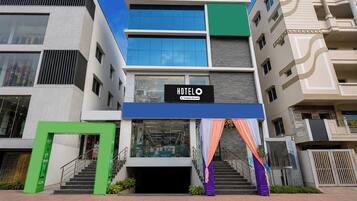 A multi-story hotel with a prominent 'HOTEL' sign, a staircase leading to the entrance, and a modern architectural design.
