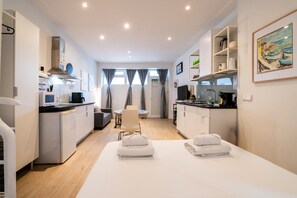 A compact hotel room with a kitchenette, a dining area, and a bed with towels. - GuestReady - Independent studio near Retiro (Madrid)