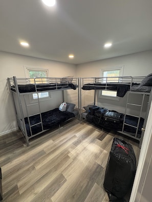 A room with two bunk beds, a suitcase, and a bag on the floor. - The Wildcat Den @Wildcat Hideout (East Bernstadt)