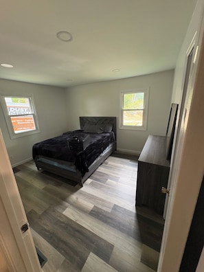 A bedroom with a bed, a dresser, and two windows. - The Wildcat Den @Wildcat Hideout (East Bernstadt)