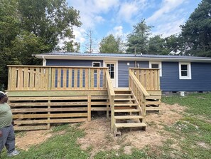 A residential building with a wooden deck and a staircase leading to a front door. - The Wildcat Den @Wildcat Hideout (East Bernstadt)