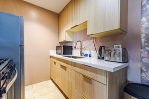 Eine kleine Küche mit integriertem Mikrowellenherd, Toaster und Spüle.