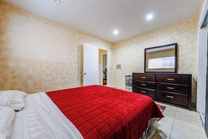 Ein Schlafzimmer mit Bett, Kommode und Spiegel an der Wand.