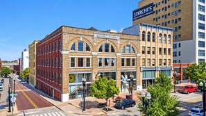 A multi-story building with a prominent 'EMPORTUM' sign, featuring a mix of brick and modern glass facades, located in an urban setting with visible street and parked cars. - Street View Condo | Walk to Knoxville’s Best (Knoxville)