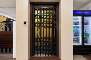 Entrada de un hotel con una reja metálica y una máquina expendedora a la derecha.