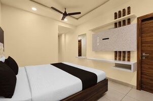 Un dormitorio con cama, ventilador de techo, televisor montado y estantes empotrados.