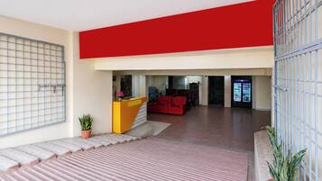 Un interior moderno con una recepción, un sofá rojo y una máquina expendedora.
