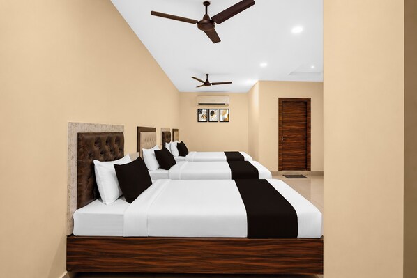 A hotel room with a large bed, two ceiling fans, and a door with a wooden panel.
