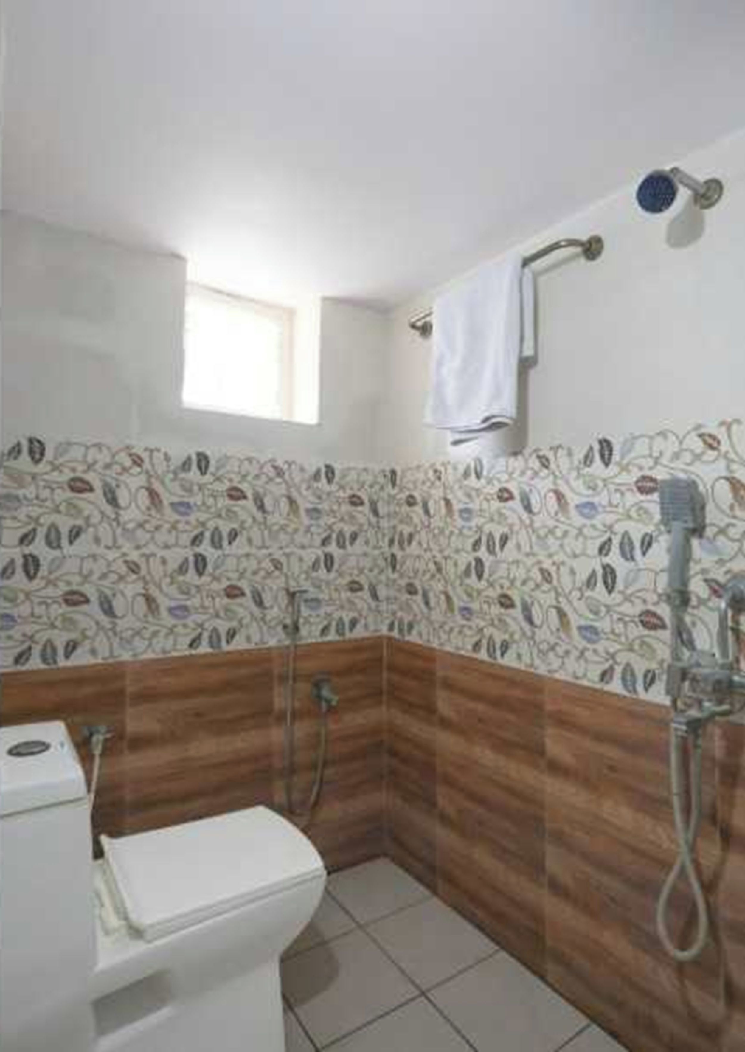 A bathroom with a toilet, shower, and a patterned wall.