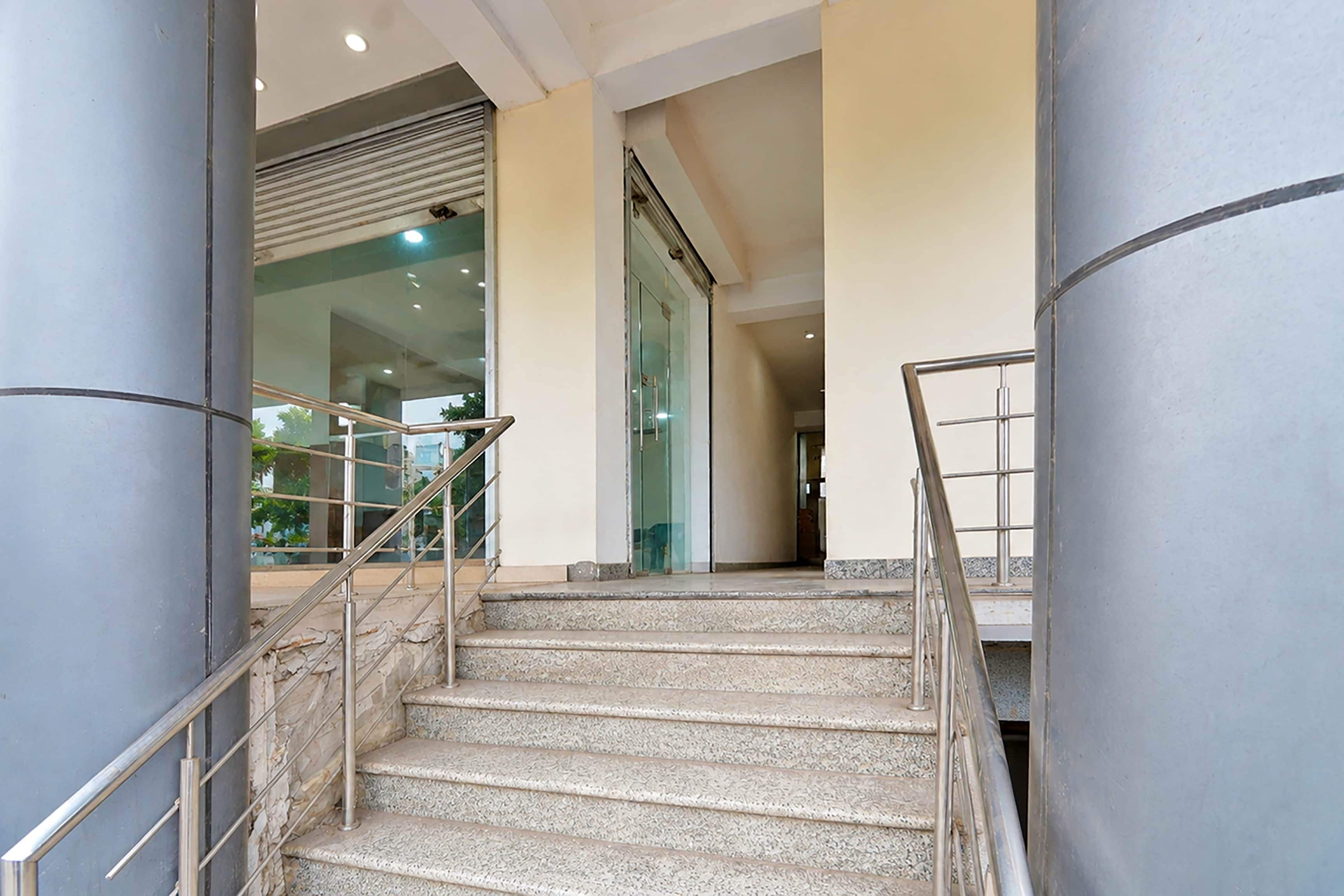 A staircase with metal railings leading to an interior space with glass doors and a view of greenery outside.