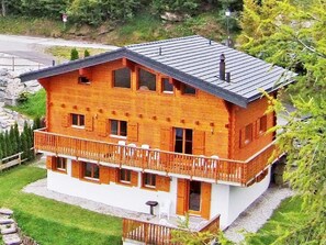 A two-story wooden house with a balcony, surrounded by greenery. - Chalet Michelle by Interhome (La Tzoumaz)