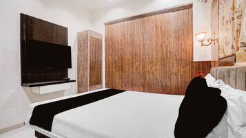 Une chambre moderne avec un lit, un téléviseur à écran plat fixé au mur, des armoires en bois et une applique murale décorative.