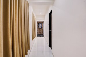 Un pasillo con una serie de cortinas a un lado y una puerta al otro.