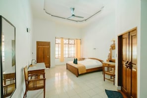 A bedroom with a bed, a desk, a chair, a wardrobe, and a window.