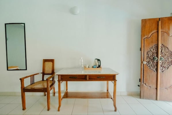 A room with a wooden desk, a chair, a wardrobe, and a mirror on the wall.