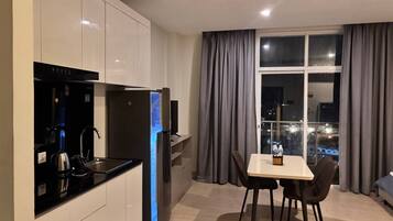A modern kitchen with a built-in oven, a coffee machine, and a dining area with a table and chairs.