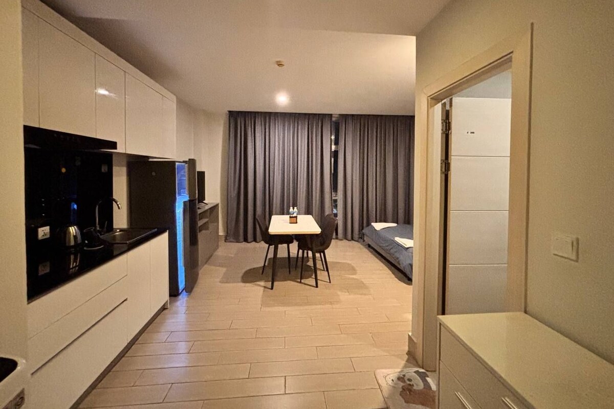 A compact hotel room with a kitchenette, a dining area, and a bed.
