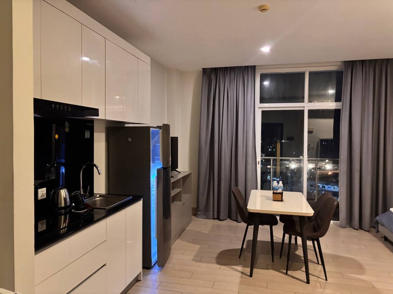 A modern kitchen with a built-in oven, a coffee machine, and a dining area with a table and chairs.