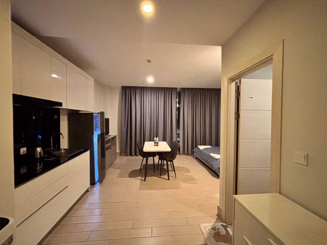A compact hotel room with a kitchenette, a dining area, and a bed.